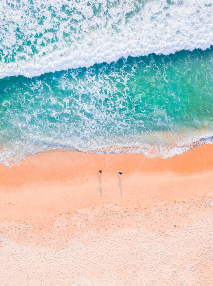 beach desktop wallpaper waves crashing into the sandy beach two people walking on the beach photographed from above