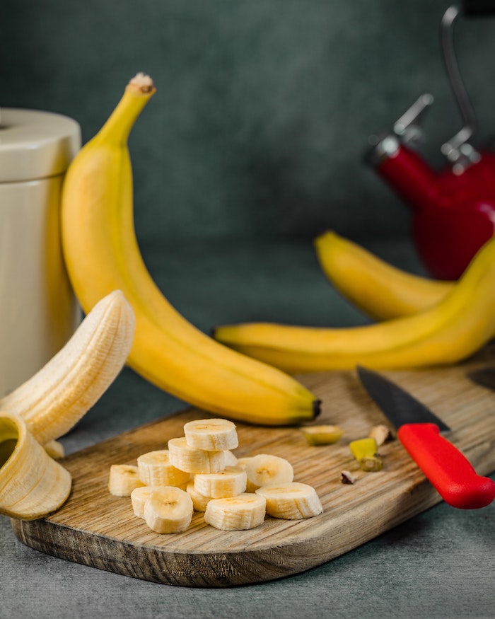 best hair mask for dry hair banana chopped up on wooden cutting board other bananas around it on table