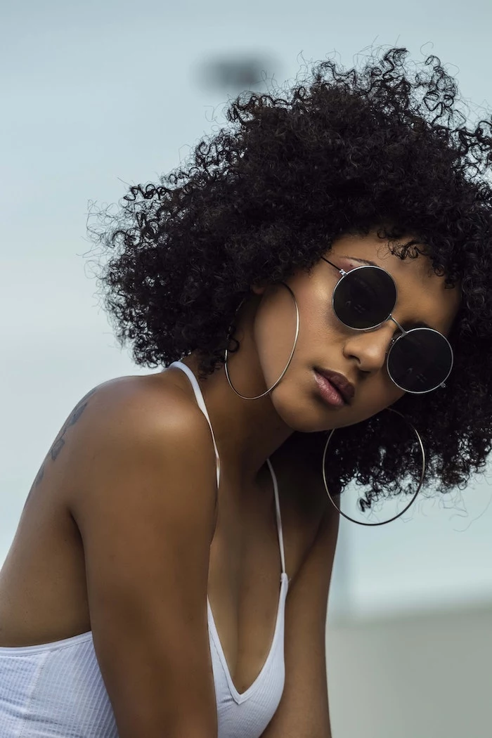 black very curly hair on woman wearing sunglasses hoop earrings white top homemade hair mask