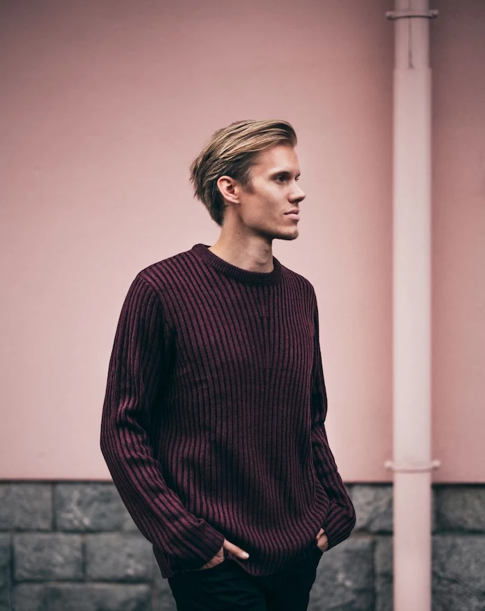 blonde man photographed on the street hair mask for curly hair wearing dark purple sweater black jeans