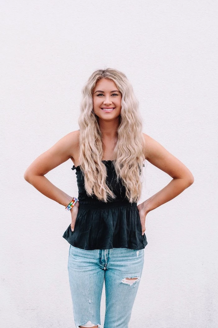 blonde woman with very long hair crimped hair 90s wearing jeans and black top