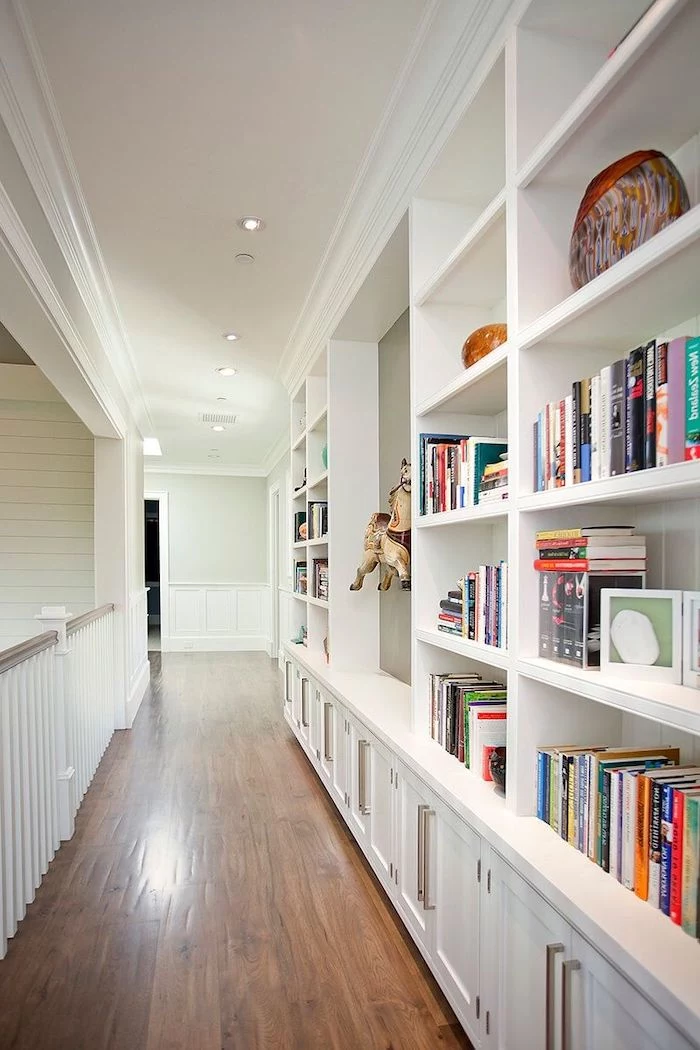 bookcase along the length of the hallway with white shelves cupboards entry way decorating ideas wooden floor