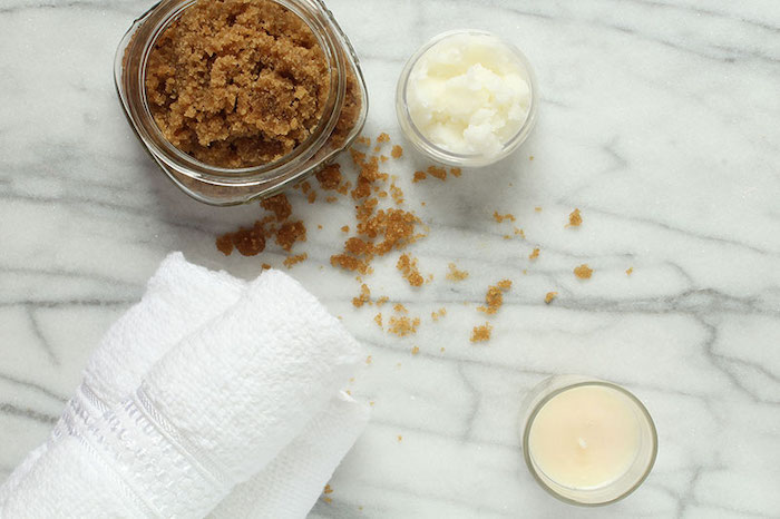 brown sugar in jar coconut oil in small bowl best hair mask for dry hair towel and candle on the side