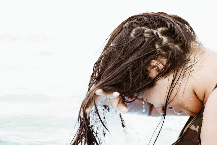 brunette hair being washed in the water best hair mask woman wearing camouflage top