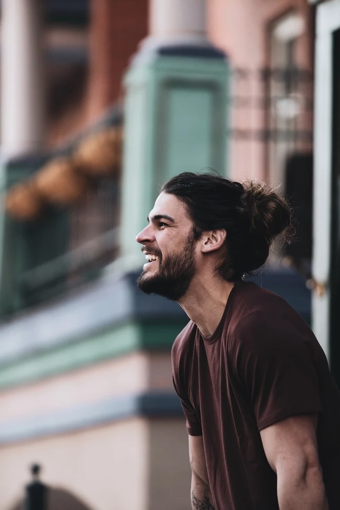 brunette man wearing his long hair in bun homemade hair mask wearing brown t shirt