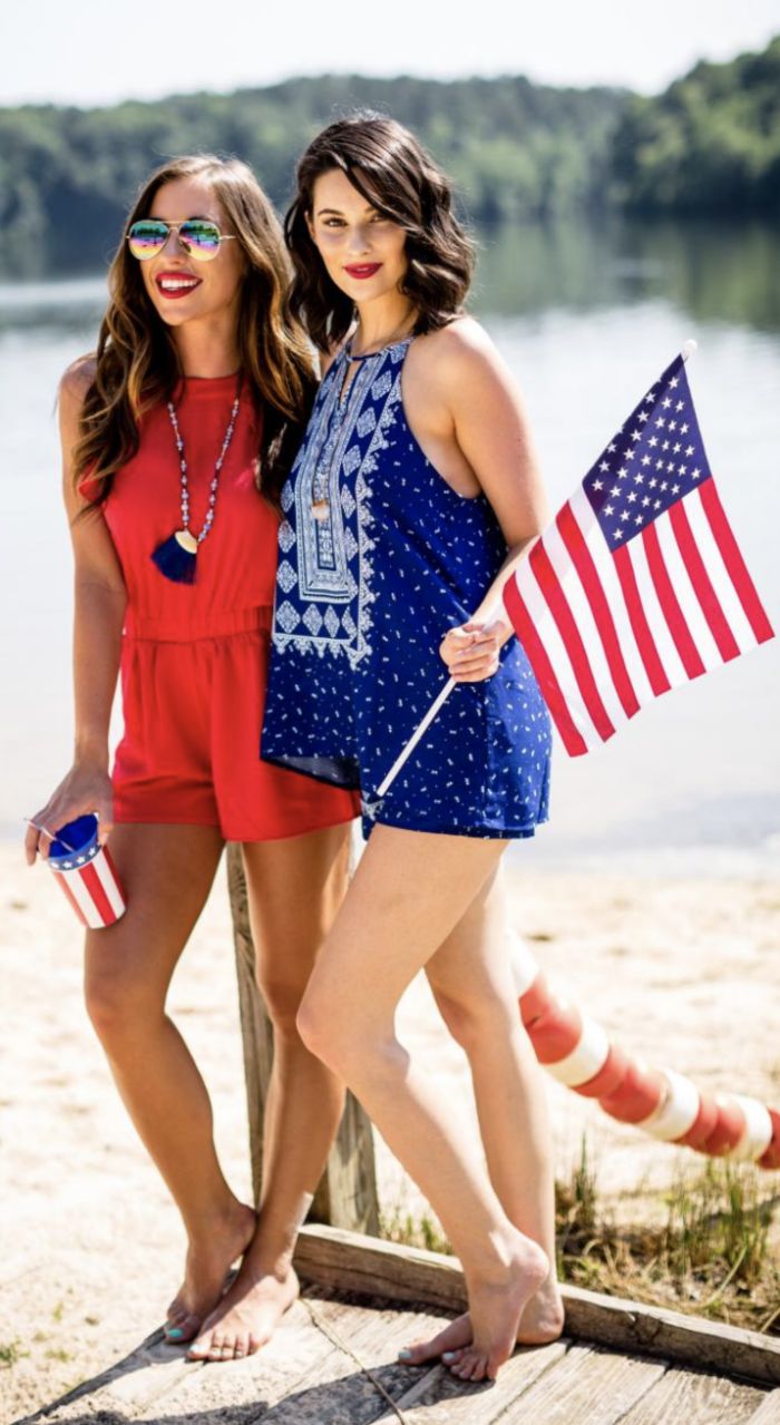 brunette women standing next to the beach 4th of july outfits wearing red and blue outfits holding american flag