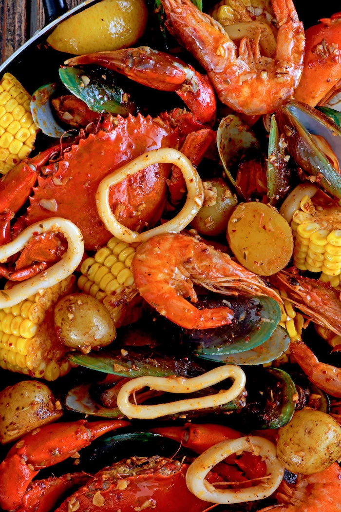 close up photo of cajun seafood boil with crabs shrimp mussels corn potatoes squid rings