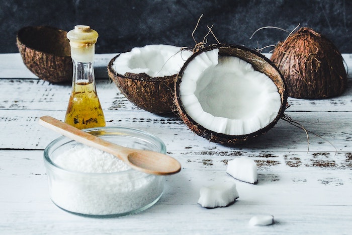 coconuts split in half placed on white wooden surface home remedies for dry hair
