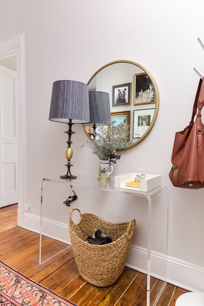 colorful rug on the floor entryway wall decor round mirror hanging on white wall above plastic shelf gray lamp on it