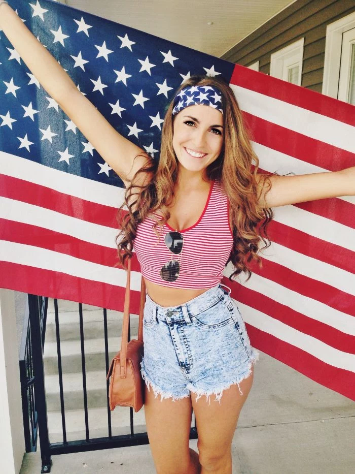 denim shorts red and white striped top worn by woman holding the american flag fourth of july outfits