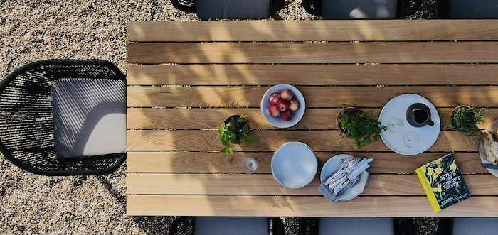 farmhouse garden table wooden table with bowl full of apples potted plants white plates on it chairs around it