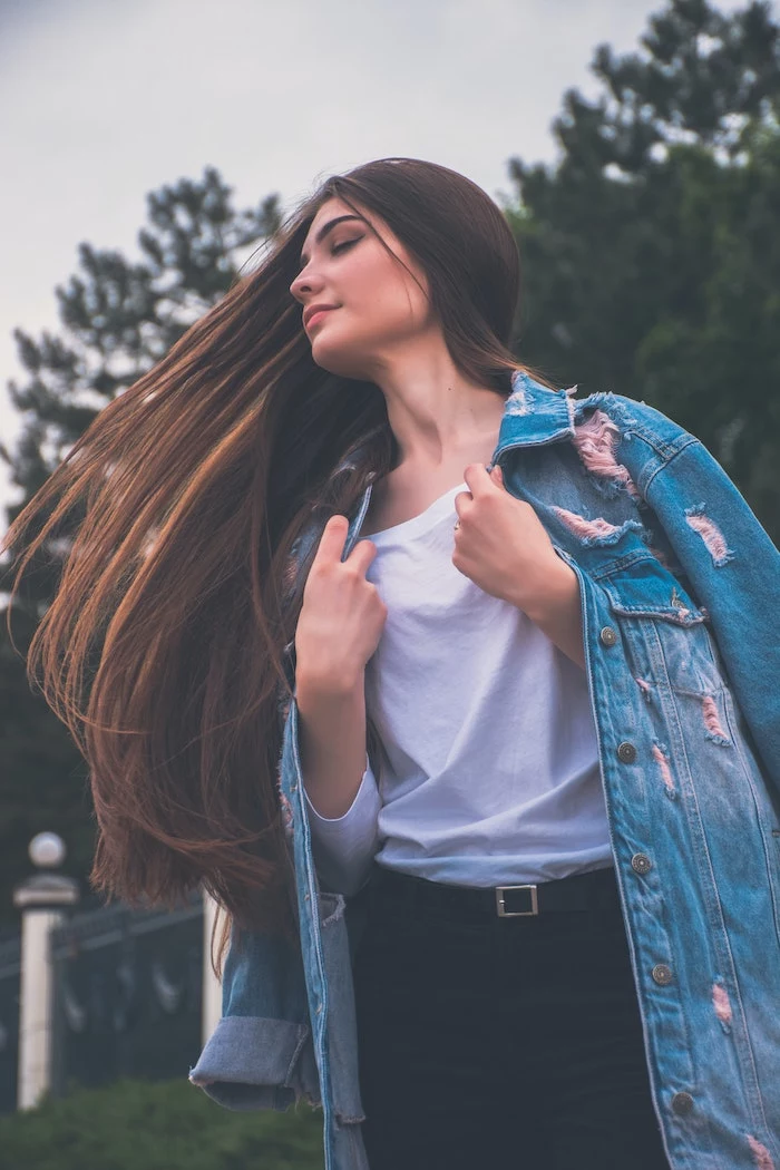 girl with very long brunette hair hair mask for curly hair wearing white t shirt black jeans denim jacket