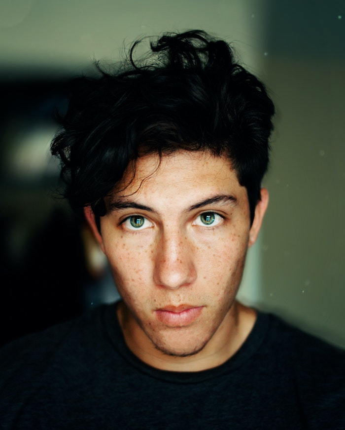 green eyed man with short curly black hair best hair mask freckles on his face