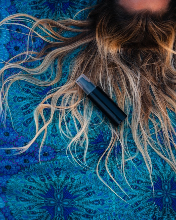 hair with balayage spread out on surface covered with blue blanket diy hair mask spray bottle placed on it