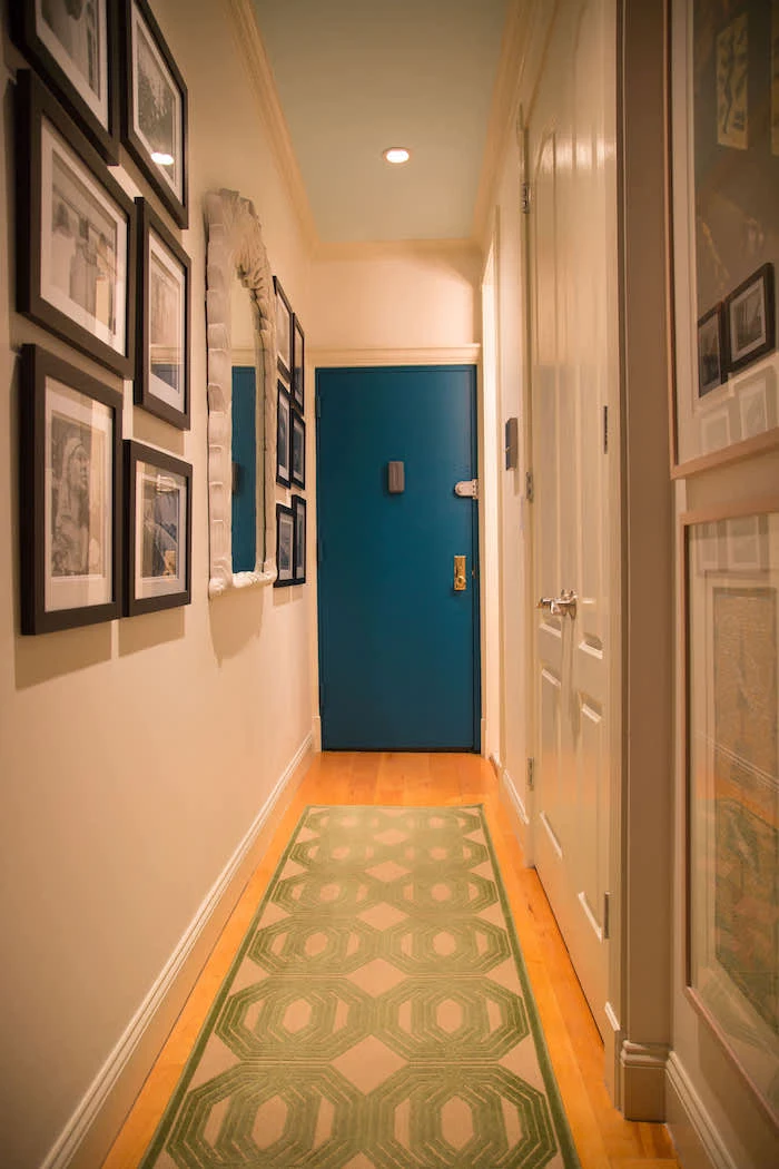 hallway wall decor ideas blue door white walls green rug on the wooden floor framed art on the walls