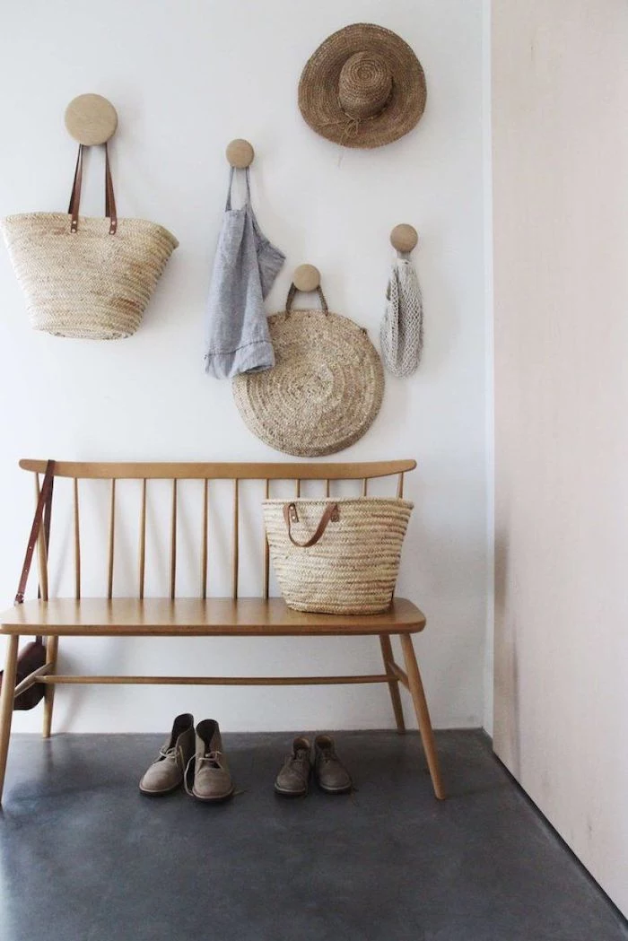 hats and bags hanging on white wall above wooden bench placed on black floor entryway decor