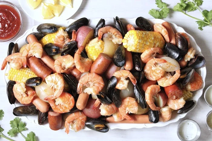 large plate with mussels shrimp sausages crab boil recipe potatoes corn on the cob