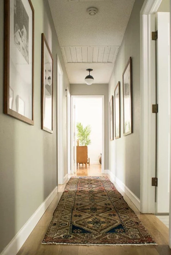 light green walls with framed art on them hallway decor ideas colorful rug on the wooden floor