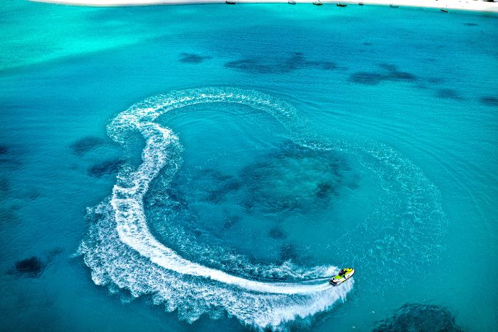 person riding jet ski in turquoise cleat water iphone beach wallpaper leaving trail behind