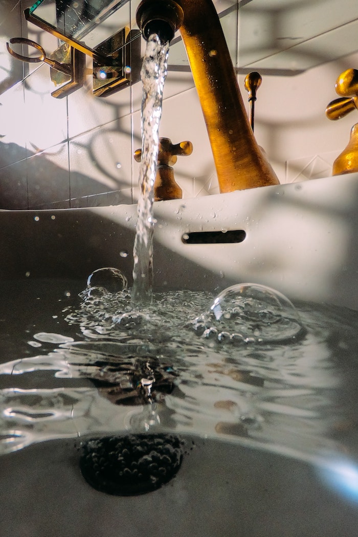 professional plumbing services tap water running from brass metal tap into the sink