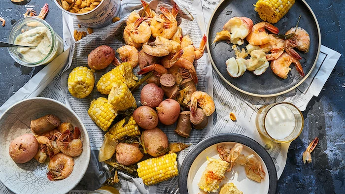 seafood boil recipe table with different plates on it boiled potatoes shrimp corn on the cob