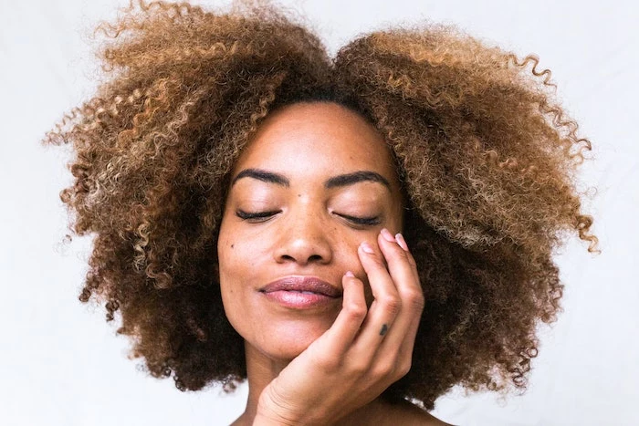 short very curly dark blonde hair diy deep conditioner woman leaning her head on her hand