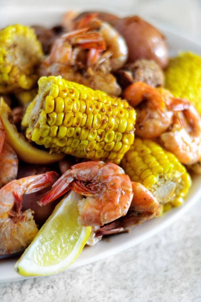 shrimp corn on the cob with lemon wedges placed on white plate shrimp boil recipe