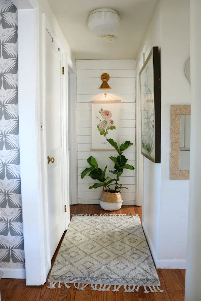 small hallway wall decor framed art on the walls potted plant white rug on wooden floor shiplap on one wall