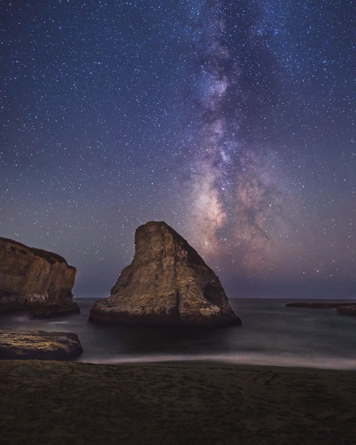 summer aesthetic wallpaper rocks in the water waves crashing into the beach sky with galaxy and stars