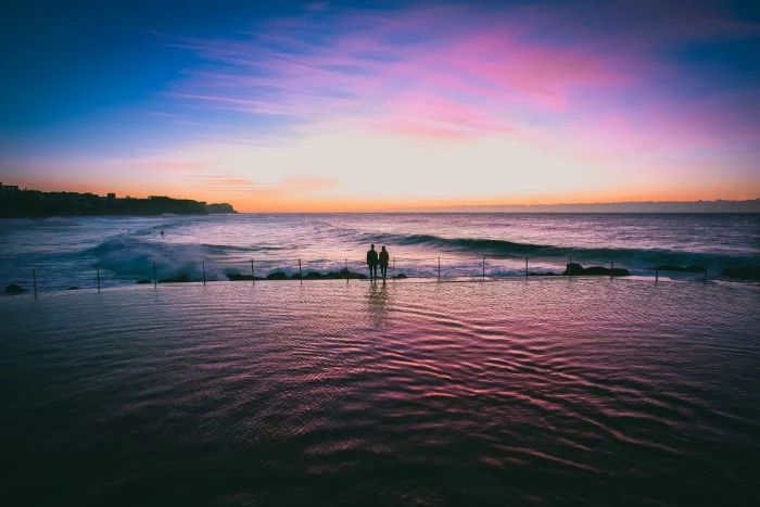 sunset photo beach wallpaper hd man woman standing in infinity pool overlooking the ocean