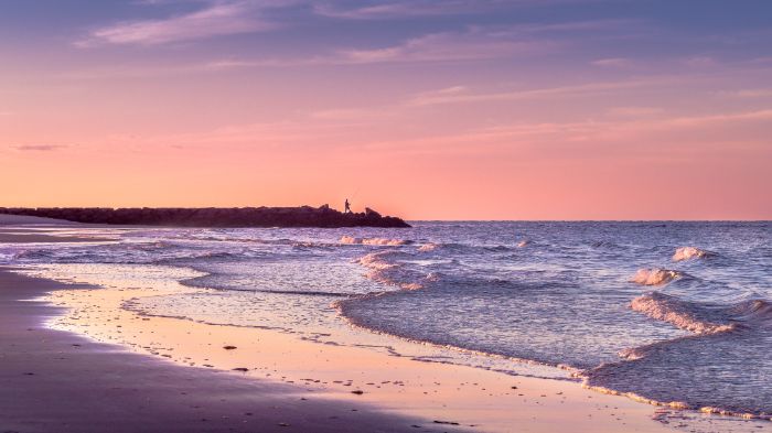 sunset view beach aesthetic wallpaper waves crashing into the beach man standing on rocks