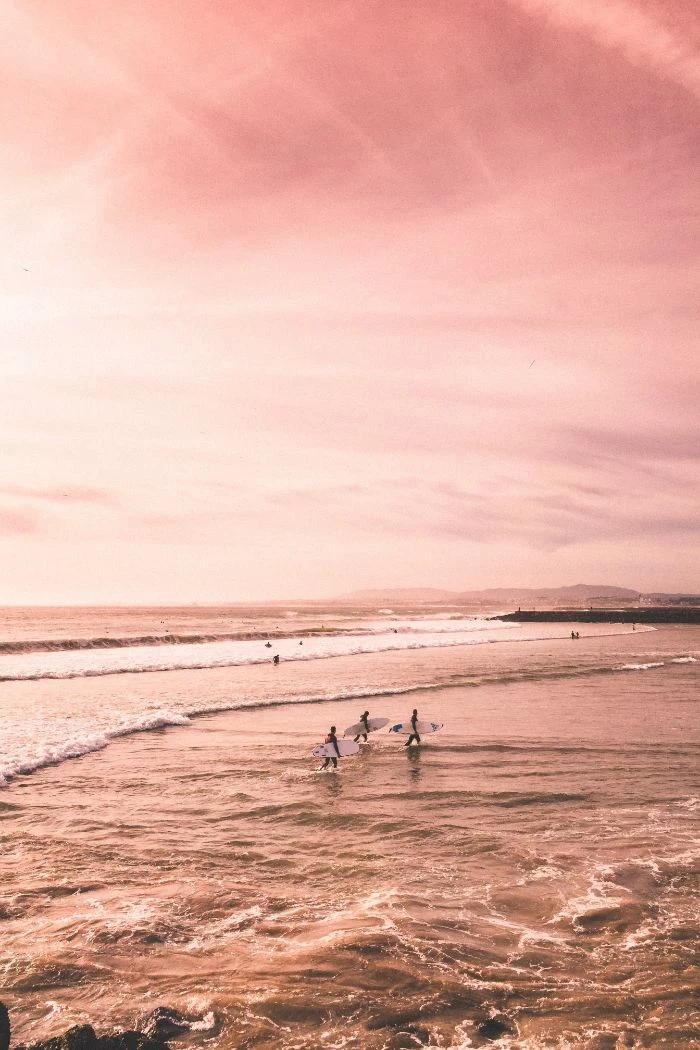 three surfers coming out of the ocean holding surfboards beach desktop wallpaper sunset photo
