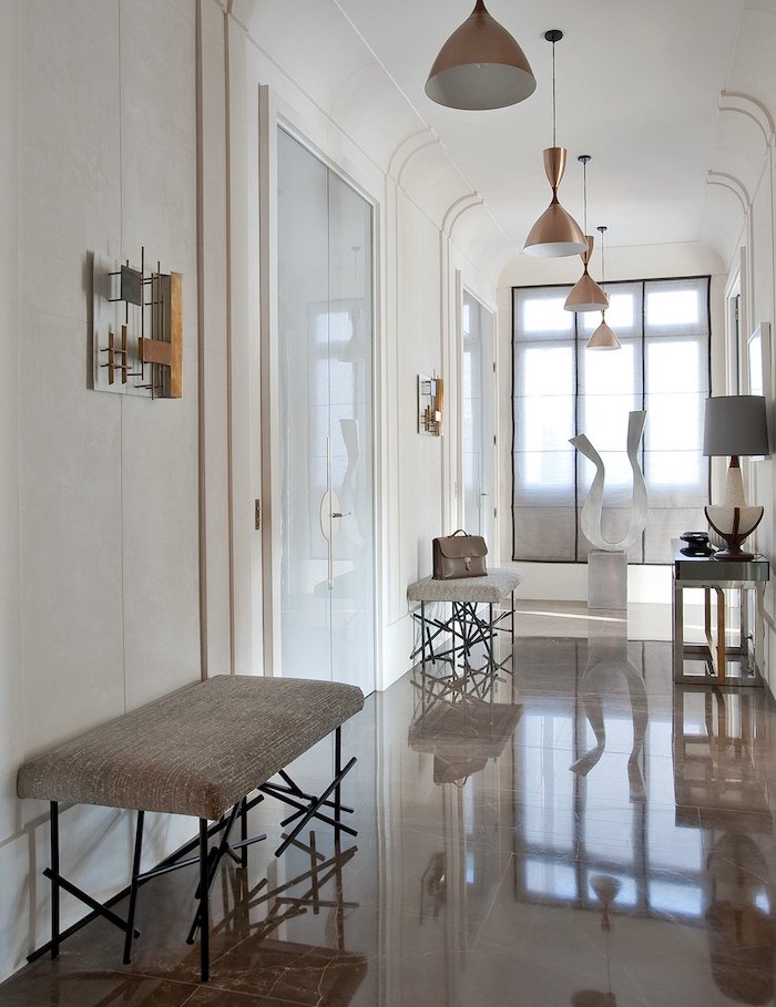 tiled floor with white walls brass light fixtures entryway decor benches along the hallway