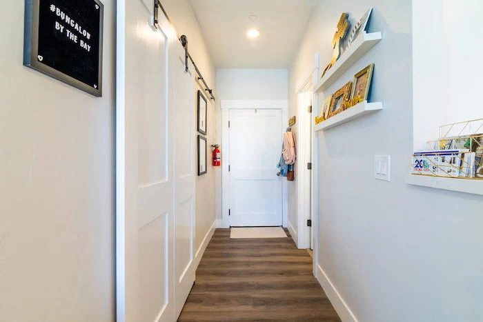 wall mounted shelves on white wall hallway decor ideas photo frames arranged on them wooden floor
