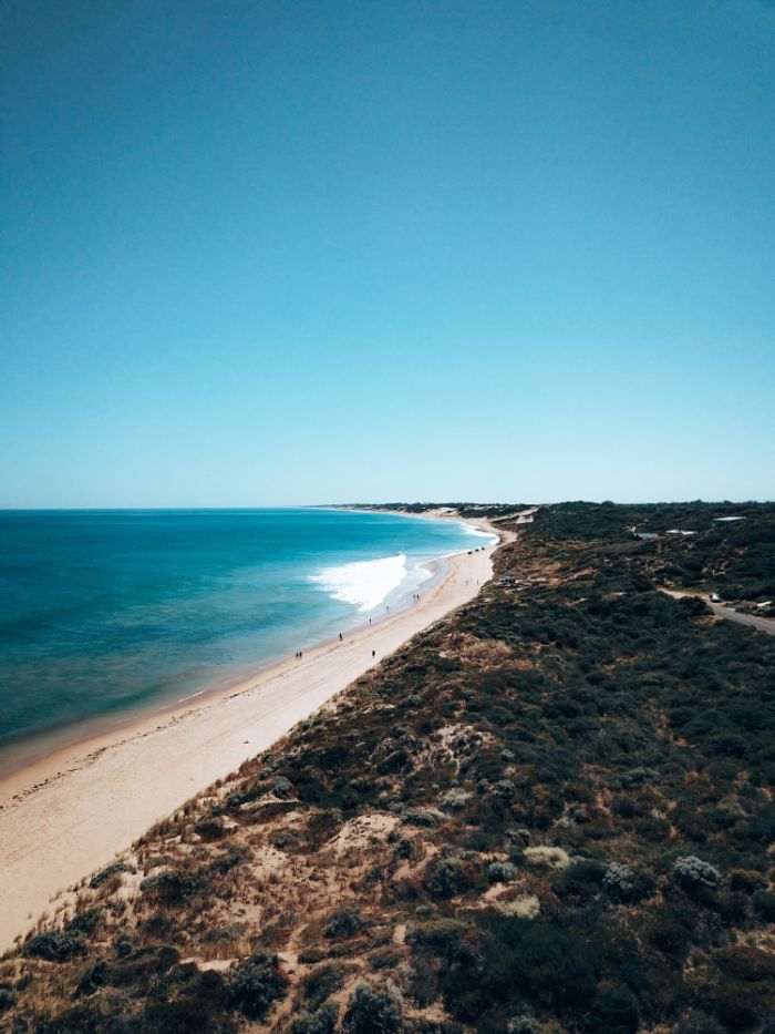 waves crashing into almost empty beach surrounded by greenery beach background hd