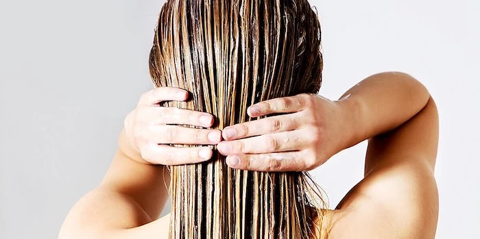 rear view of woman applying conditioner on hair against white background