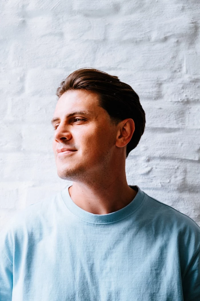 white brick wall for background hair mask for curly hair man with short brown hair wearing blue t shirt