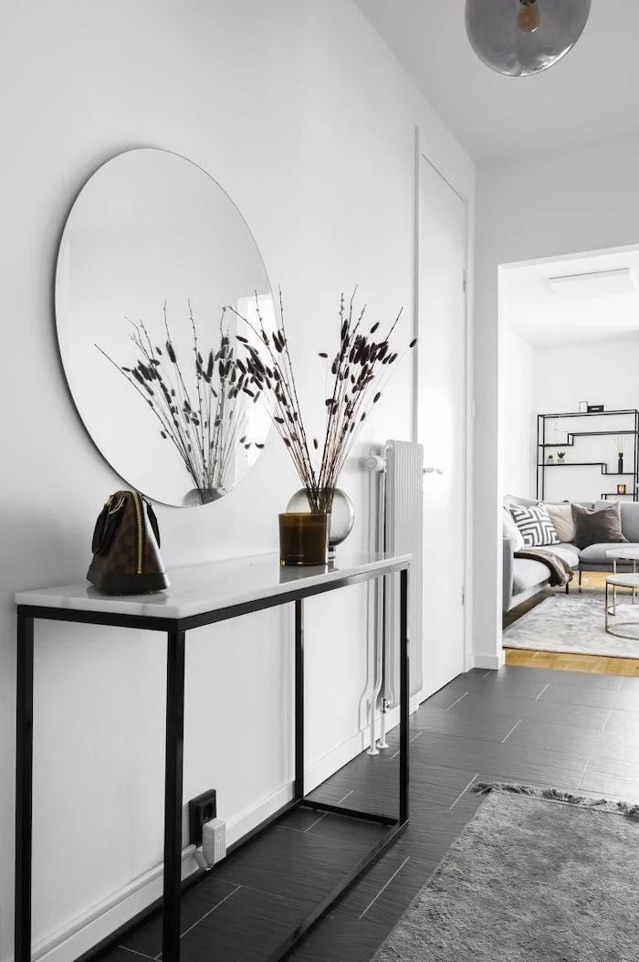 white walls large round mirror hanging above table entryway design ideas black tiles on the floor gray rug