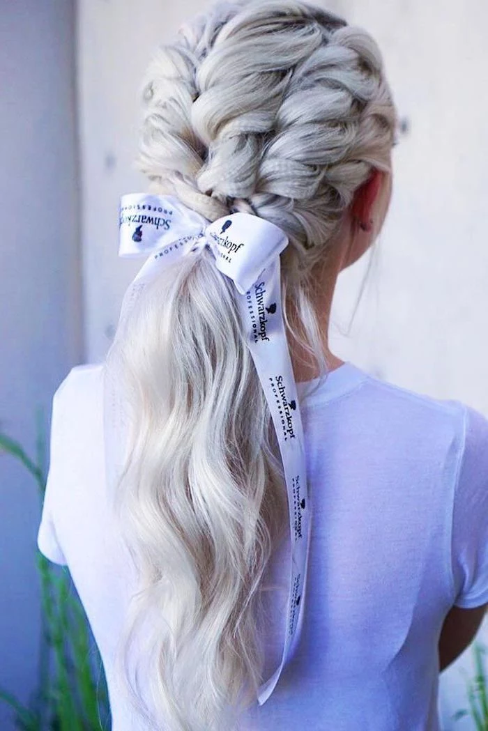 woman with long blonde hair short crimped hair four braids tied in low ponytail with white bow