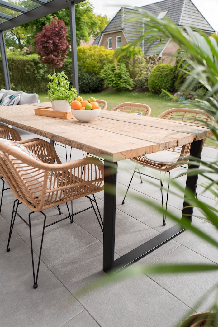 wooden table and chairs on concrete tiles farmhouse garden table bowl full of fruits on top