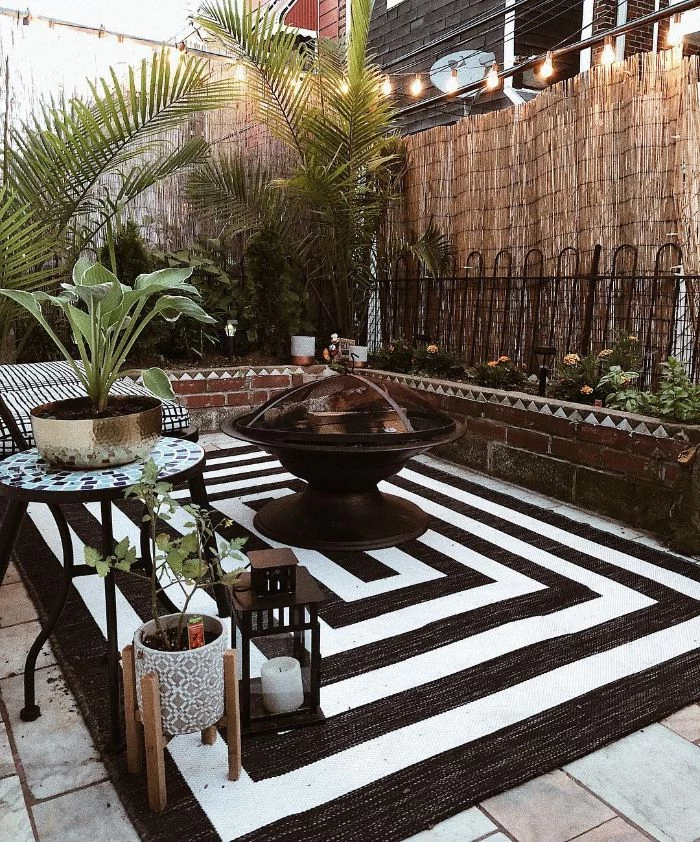 black and white rug under fire pit black metal bench table next to it backyard ideas on a budget lanterns