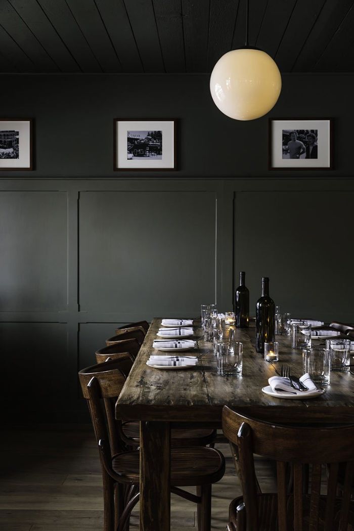 black walls with black and white photographs dining room table decor vintage salvaged wood table and chairs