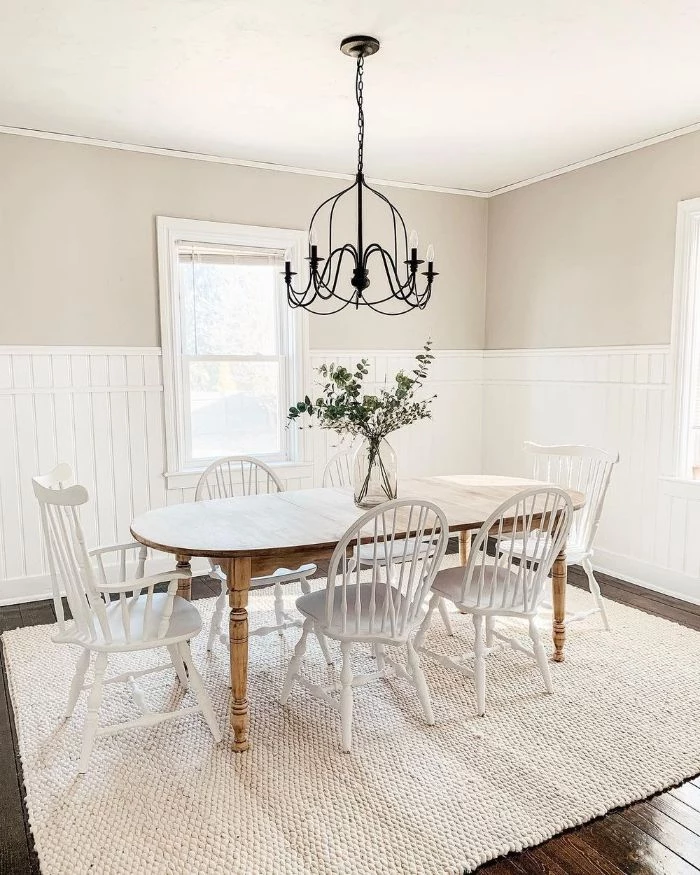 chandelier hanging above table with white wooden chairs around it dining room table decor shiplap on the walls