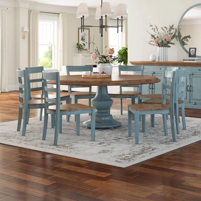 farmhouse dining table round table blue chairs placed on rug vase filled with flowers on top of table