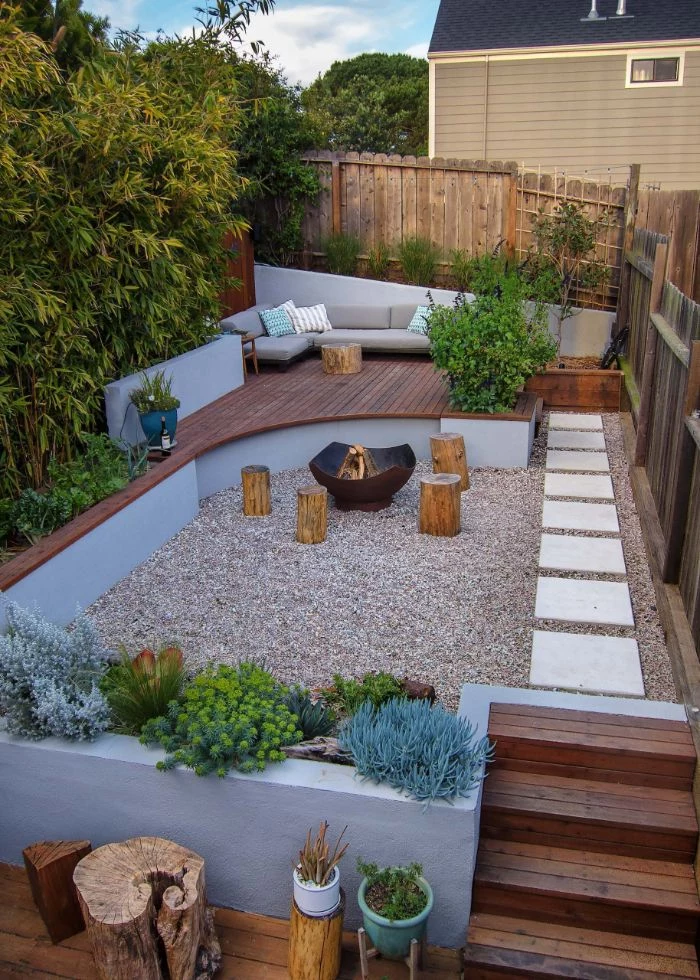 fire pit with four wooden logs around it backyard patio ideas lounge area with gray sofa