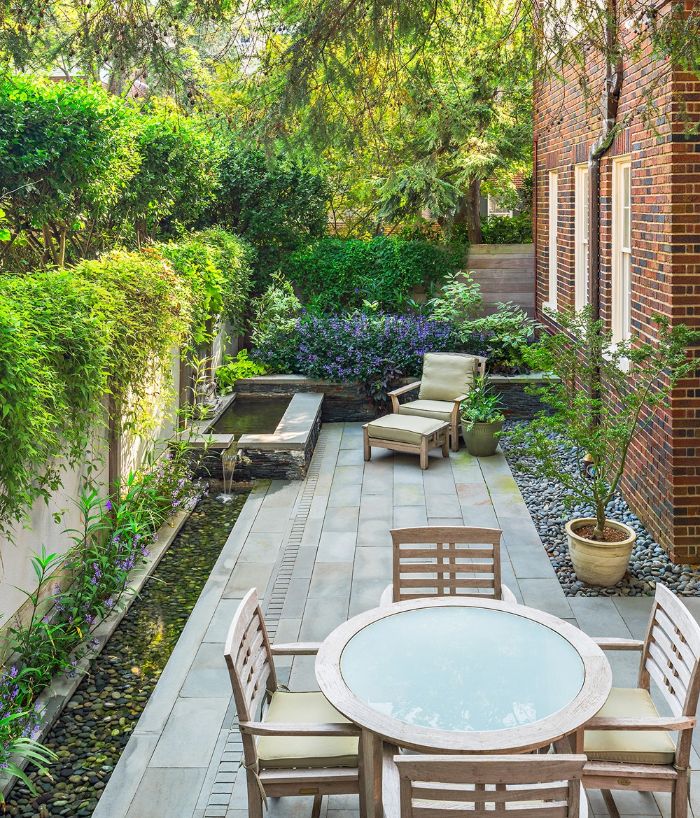 fountain with lounge chair next to it dining area backyard décor ideas surrounded by flowers and trees