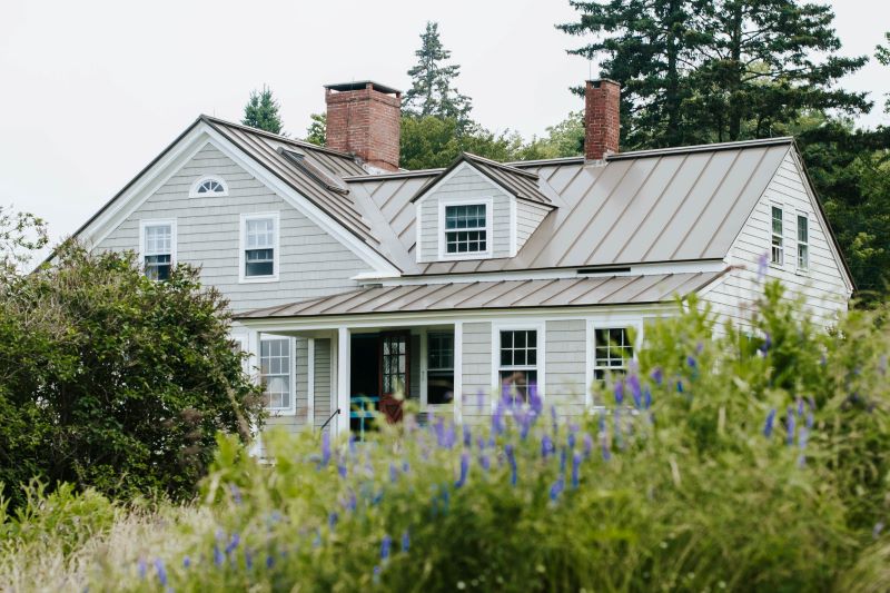 gray house remodeling expenses surrounded by bushes trees