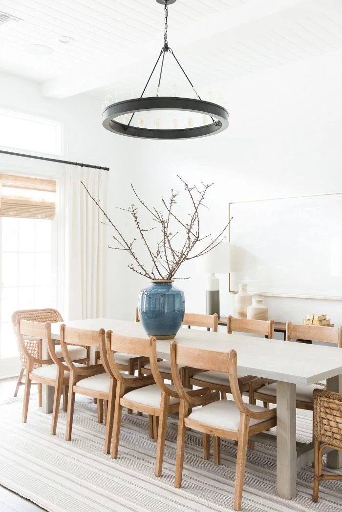 large vase placed on long table with wooden chairs farmhouse dining table hanging chandelier