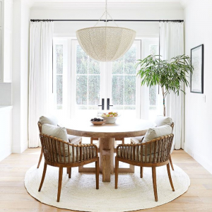 large windows with white curtains farmhouse dining room round wooden table and chairs with gray cushions