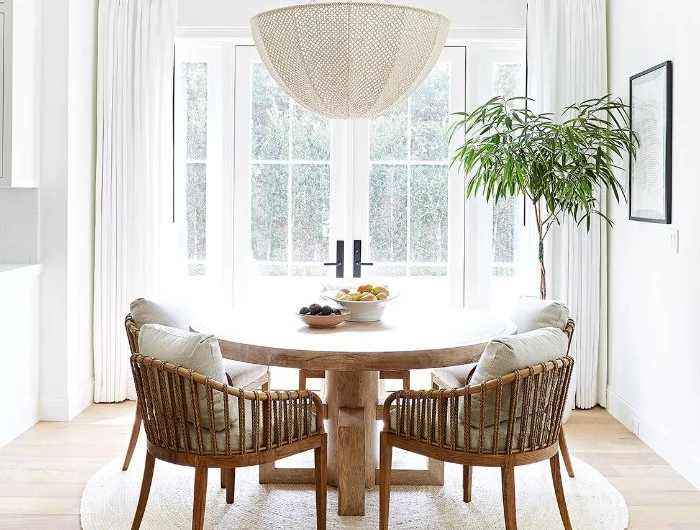 large windows with white curtains farmhouse dining room round wooden table and chairs with gray cushions